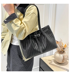 Detail of black woven texture on a large tote bag with buckle and shoulder strap