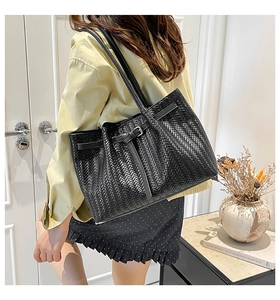 Close-up of black woven tote bag with silver buckle and elegant leather straps