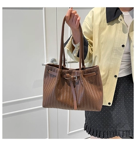 Detail of brown woven tote bag showing faux leather texture and metallic buckle strap