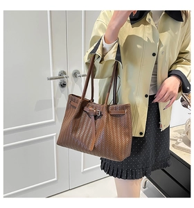 Detail of dark brown woven leather tote bag with V-shaped texture and adjustable strap