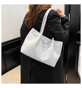 Detailed close-up of a white woven tote bag with adjustable straps on a model in a black suit
