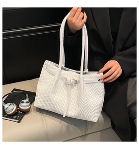 Close-up of white woven tote bag with herringbone pattern and decorative buckle detail