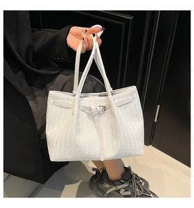 Detail of woven white tote bag showing fine chevron pattern and decorative buckle