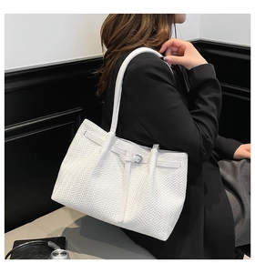 Detailed close-up of the white woven texture and metallic buckle on a large tote bag