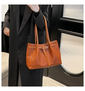 Close-up of brown woven leather tote bag with silver buckle and shoulder straps