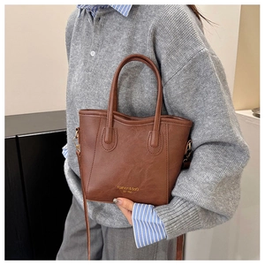 Close-up of retro brown leather bucket bag with gold lettering and slim shoulder strap
