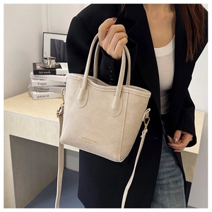 Detail of cream tote bag featuring gold Fashion & Bag lettering and textured PU leather