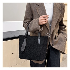 Close-up of black fleece tote bag texture with fashion tag and leather handle detail