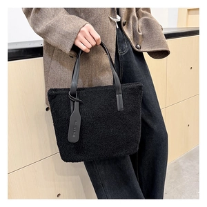 Detailed close-up of the black plush bucket bag showing rich faux fur and leather handles