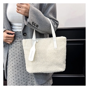 Detail shot of the white plush faux fur tote bag with stylish leather handle and tag