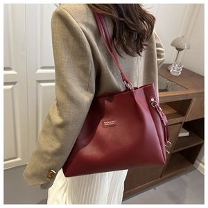 Bolso tote rojo oscuro combinado con blazer beige y falda plisada blanca en un ambiente cálido