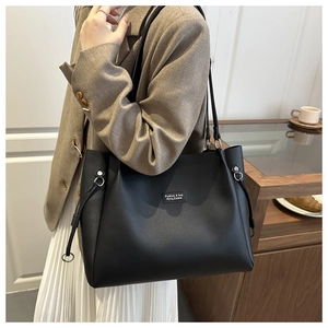 Vista detallada del bolso tote de cuero negro con etiqueta cuadrada y cordones decorativos