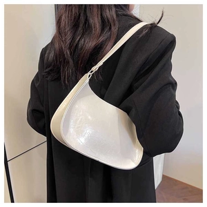 Close-up of cream semi-moon underarm bag showing glossy faux leather texture and strap