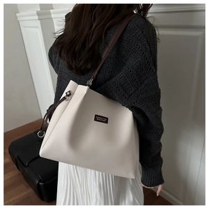 Detailed shoulder view of a large cream tote bag with contrast brown straps and logo