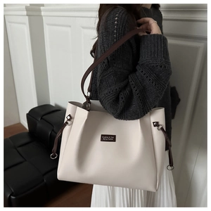 Detalle del bolso tote blanco crema con correas marrones y etiqueta de logo de moda