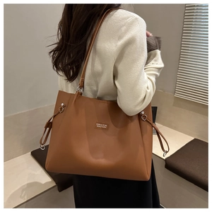 Detalle de un bolso tote marrón con elegantes cordones laterales y un parche de logo frontal