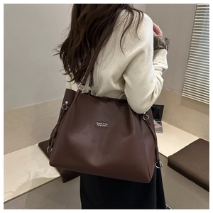 Detail view of large dark brown leather tote bag showing texture and side metal ring buckle