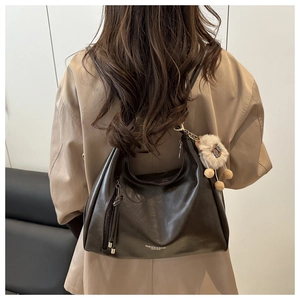 Detail of dark brown matte leather hobo bag with tassel and plush toy charm on back