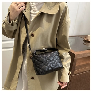 Close-up of black crossbody bag featuring heart quilted pattern and gold metal lock detail