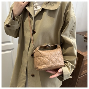 Detail of heart quilted beige bucket bag with gold handle and leather texture