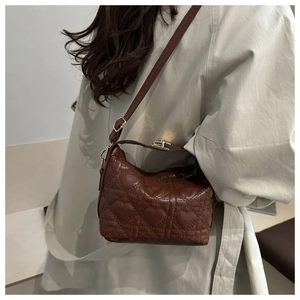 Détail du sac bandoulière marron foncé avec matelassage en cœur et accents dorés