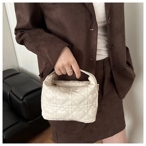 Détail du sac à main crème avec surpiqûres en cœur, zip doré et mini poignée supérieure