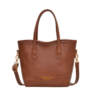 Brown leather bucket tote bag with dual handles and gold lettering on white background