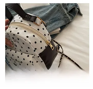 Detailed view of white polka dot backpack with chain strap and cat motif on front pocket