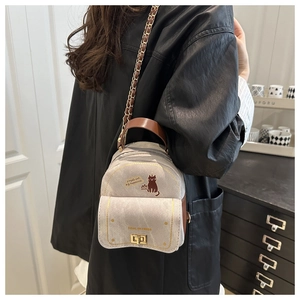 Détail du sac à dos en toile grise avec imprimé chat et chaîne dorée sur mannequin
