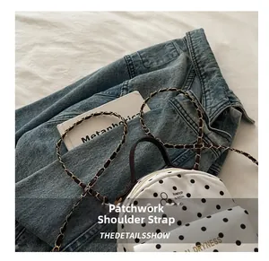 Detail view of the white polka dot backpack with gold metal and leather chain strap