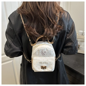 Detailed back view of a mini white polka dot backpack with a gold chain strap and cat print