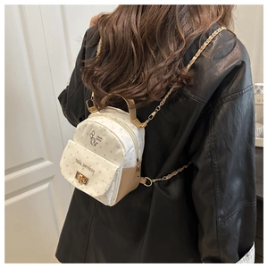 Polka dot backpack with cat illustration, gold chain straps, worn over a black leather jacket