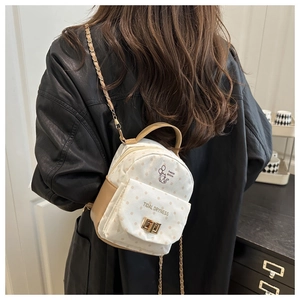 Detail of a beige polka dot mini backpack with cat print and gold chain straps
