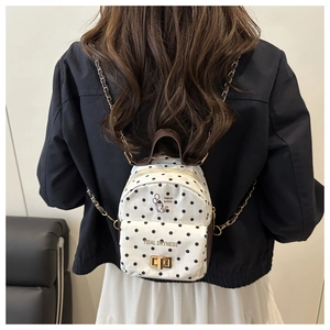 Detail of white polka dot backpack featuring metal chain strap and cute kitten prints