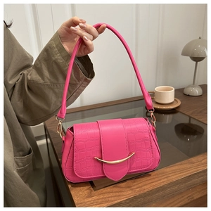 Détail macro du sac rose en cuir façon crocodile avec fermoir métallique doré en forme de U