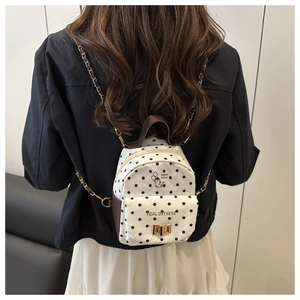Close-up of mini polka dot canvas backpack with cartoon cat print and gold chain strap