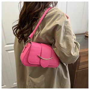 Détail du sac en cuir de crocodile rose avec fermoir en métal doré porté à l'épaule