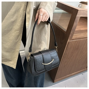 Gros plan sur un sac à main noir motif crocodile avec boucle en métal doré courbé