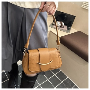 Détail du sac baguette marron avec gaufrage crocodile et fermoir doré dans un bureau
