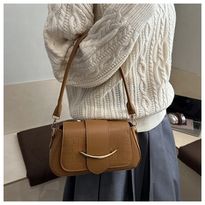 Détail de la texture crocodile marron et du fermoir métallique doré de ce sac chic