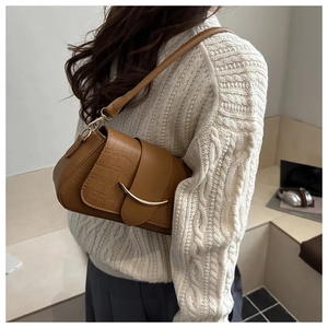 Sac à bandoulière marron motif croco avec boucle dorée en croissant sur un tricot