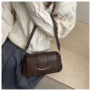 Détail du sac marron foncé à motif crocodile avec boucle en métal doré en forme de croissant