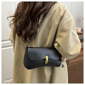 Minimalist black leather shoulder bag with vintage gold buckle shown on a trench coat