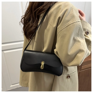 Detail of elegant black underarm bag featuring a stylish golden U-shaped metal buckle