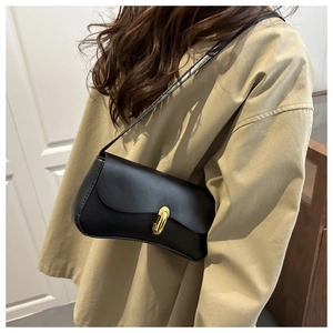 Detail of a minimalist black underarm bag with a golden oval metal clasp closure