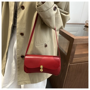 Detail of red leather crossbody bag with gold capsule lock and matte finish on model