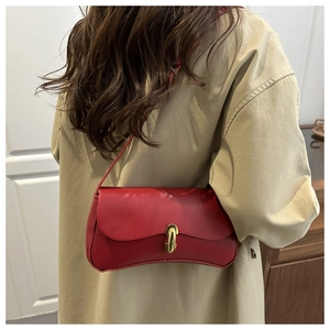 Detail view of a bright red leather underarm bag with a vintage gold oval metal buckle lock