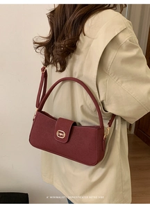 Burgundy faux leather shoulder bag with gold horsebit buckle styled with a beige coat
