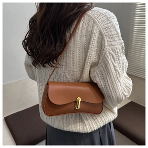 Caramel leather crossbody bag on shoulder, showing size and fit on a white knit sweater