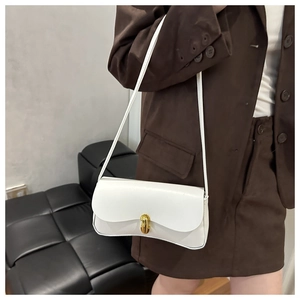 Chic white faux leather baguette bag with a gold oval clasp worn with a brown blazer
